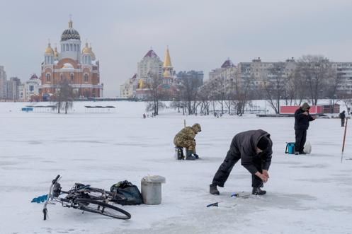 Des hommes pêchent sur un lac gelé, dans un quartier de la rive gauche de Kiev, le 11 janvier 2026.