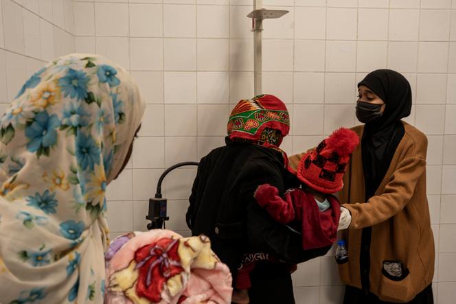 Une femme réfugiée soudanaise est pesée avec son bébé dans les bras, au centre médical Al-Azil de Koufra, en Libye, le 16 décembre 2025.