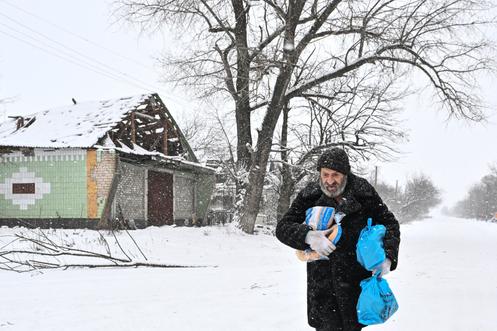 Un habitant transporte de la nourriture livrée par des policiers ukrainiens, dans le village de Dolynka, dans l’oblast de Zaporijia (Ukraine), le 16 janvier 2026.