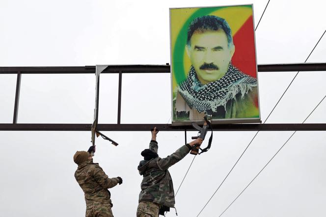 Des membres de l’armée syrienne s’apprêtant à arracher un portrait du leader kurde emprisonné Abdullah Öcalan, installé le long d’une rue à Al-Tabqa (Syrie), le 18 janvier 2026.