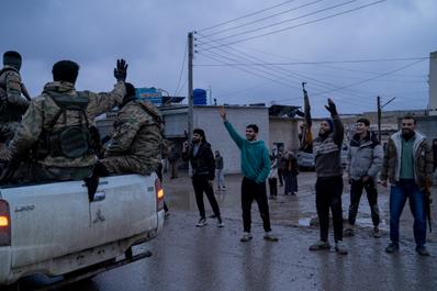 Residents of Raqqa, Syria, watch as a convoy of the Syrian army passes through the outskirts of the city on January 18, 2026.