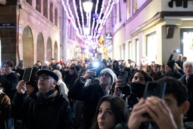 Des visiteurs prennent des photos du sapin de Noël installé lors du marché de Noël de Strasbourg, le 26 novembre 2025.