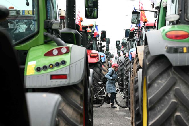 Une cycliste tente de se frayer un chemin malgré les tracteurs alignés lors d’une manifestation d’agriculteurs européens, devant le Parlement européen à Strasbourg le 20 janvier 2026.