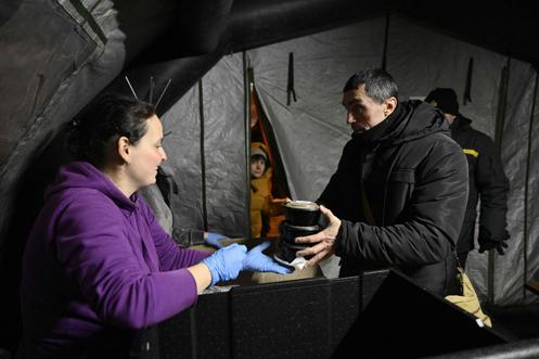 Distribution d’un repas chaud par des bénévoles, dans une tente d’urgence installée dans un quartier résidentiel de Kiev, le 22 janvier 2026.