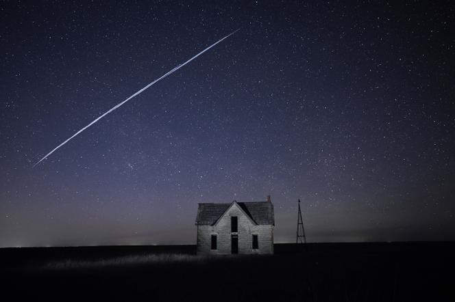 Dans cette photo à longue exposition, une série de satellites SpaceX Starlink survolent une maison, à Florence, Kansas, en mai 2021.
