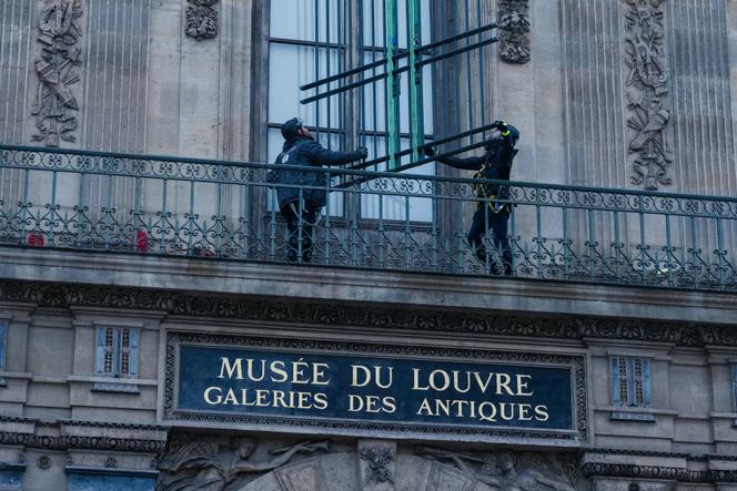 Des ouvriers installent des grilles aux fenêtres de la galerie d’Apollon au Louvre, sur la façade donnant sur le quai François-Mitterrand, à Paris, le 23 décembre 2025. 