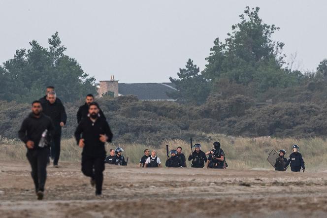 Des policiers tentent d’empêcher des personnes d’embarquer sur un bateau pneumatique pour traverser la Manche, sur la plage de Gravelines (Nord), le 29 juillet 2025. 