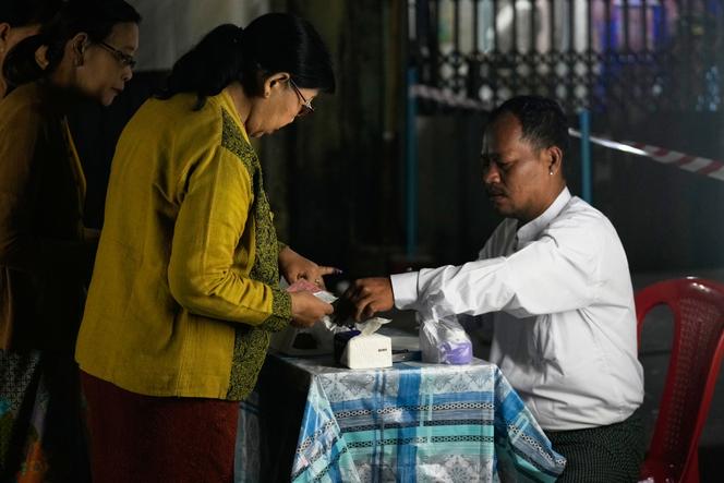 A voter dips her finger in an ink bottle after casting ballot a polling station during the third phase of general election January 25, 2026, in Yangon, Myanmar.
