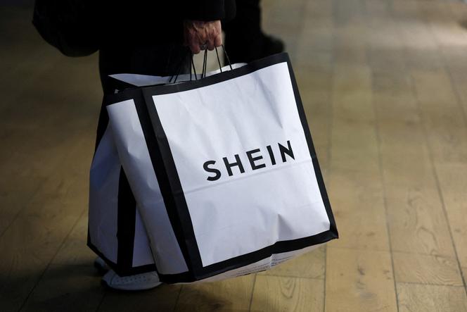Une cliente tient des sacs de courses portant le logo Shein à Paris, le 5 novembre 2025. 