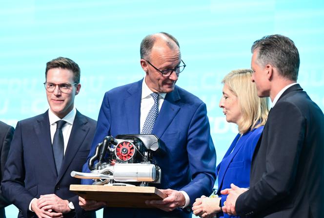 Remise d’une maquette de moteur Porsche au chancelier allemand, Friedrich Merz, par le président du land de Bade-Wurtemberg, Manuel Hagel (à gauche), à Stuttgart, le 17 mai 2025. 