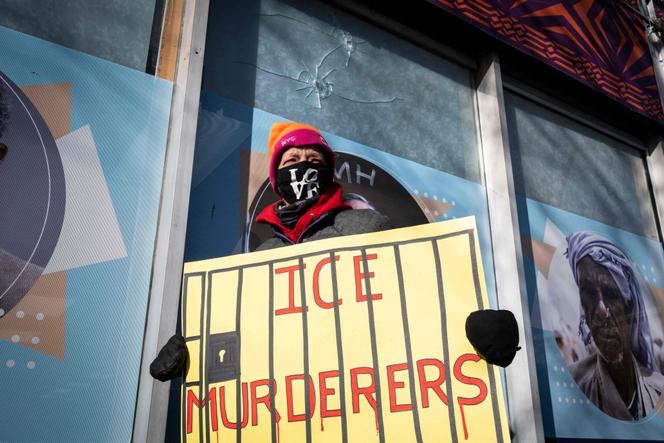 Une manifestante brandit une affiche devant une vitrine montrant deux impacts de balles, à Minneapolis (Minnesota), le 26 janvier 2026.
