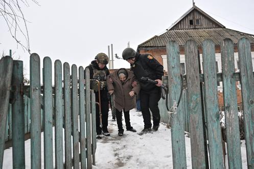 Des policiers aident une habitante à évacuer un village situé en première ligne, dans l’oblast de Zaporijia (Ukraine), le 27 janvier 2026.