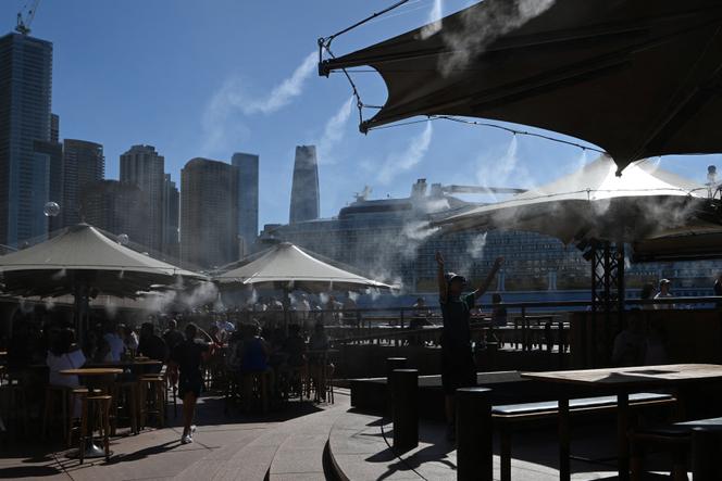 Des gens se rafraîchissent sous une brume d’eau à Circular Quay pendant une période de forte chaleur, à Sydney, le 27 janvier 2026.