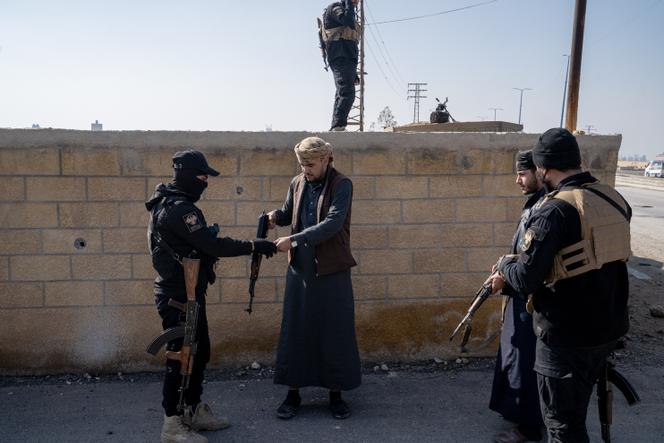 Um ex-membro das Forças Democráticas Sírias (SDF) devolve a sua arma aos membros da segurança interna do governo sírio, no âmbito do processo de reconciliação, em frente à base militar 