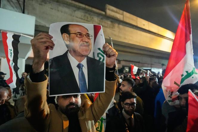 Un Irakien brandit un portrait de l’ancien premier ministre Nouri Al-Maliki lors d’une manifestation contre le président Donald Trump sur un pont menant à la zone verte fortifiée où se trouve l’ambassade américaine à Bagdad, en Irak, le 29 janvier 2026.