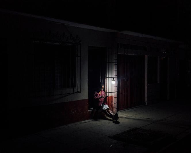 Une femme profite de la lumière de son ampoule à batterie lors d’une coupure d’électricité, à Cienfuegos (Cuba), le 10 janvier 2026.