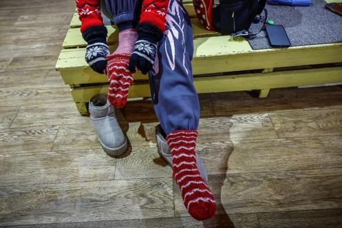 Une jeune fille enfile plusieurs paires de chaussettes et des vêtements chauds, avant son entraînement dans une salle de gymnastique sans électricité ni chauffage, à Kiev, le 29 janvier 2026.
