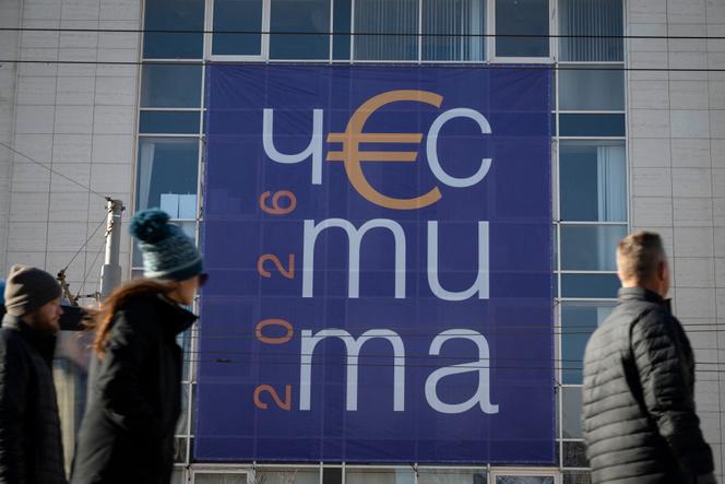 Devant un panneau en bulgare souhaitant une «&nbsp;Bonne année 2026&nbsp;», à Sofia, le 30&nbsp;décembre&nbsp;2025, avant l’adoption de l’euro par la Bulgarie le 1ᵉʳ&nbsp;janvier&nbsp;2026.