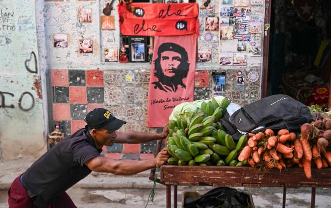 Un vendeur ambulant pousse un chariot chargé de fruits et légumes devant une boutique de souvenirs affichant des images du guérillero cubain d’origine argentine Ernesto Che Guevara à La Havane, le 5 février 2026. 