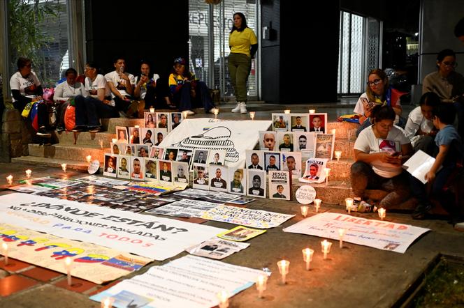 Des proches de prisonniers politiques assis à côté de photographies alors qu’ils tiennent une veillée devant le centre de détention d’El Helicoide, à Caracas, Venezuela, le 5 février 2026.