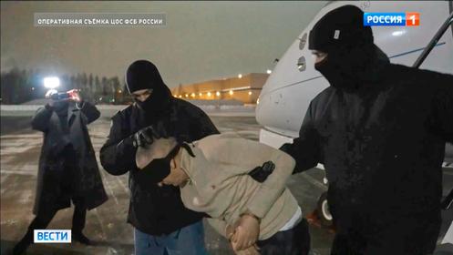 Cette image, extraite d’une vidéo diffusée par le Service fédéral de sécurité russe (FSB) via la chaîne de télévision Russia-1, montre l’auteur présumé de l’attaque contre un haut général russe, escorté par des agents du FSB à un aéroport, près de Moscou, le 8 février 2026.