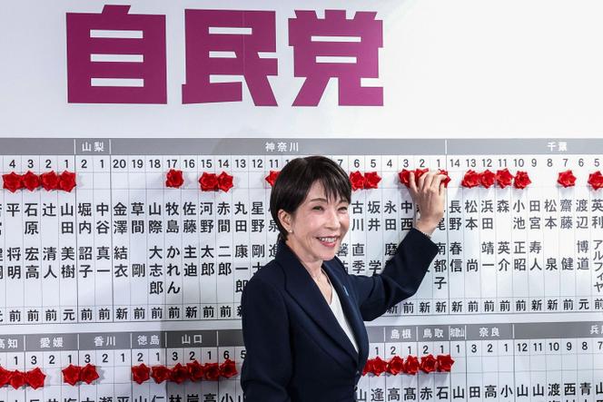 A primeira-ministra japonesa, Sanae Takaichi, coloca uma rosa de papel vermelha acima dos nomes de cada candidato eleito nas eleições legislativas na sede do seu partido em Tóquio, em 8 de fevereiro de 2026.