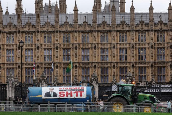 Un tracteur tire une remorque sur laquelle on peut lire «&nbsp;Starmer full of sh1t&nbsp;» («&nbsp;Starmer est un connard&nbsp;»), devant le palais de Westminster, en signe de protestation contre le premier ministre britannique Keir Starmer, à Londres, le 11&nbsp;février&nbsp;2026. 