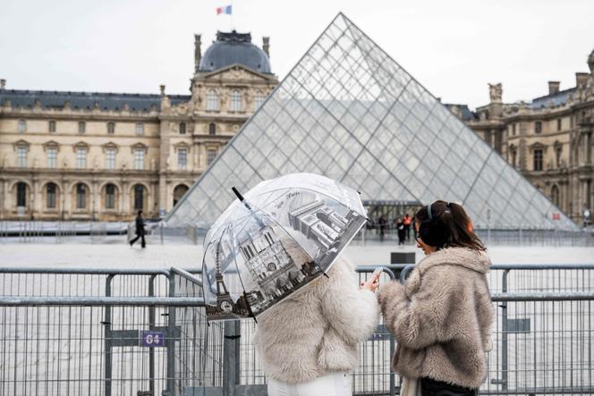 Turistas ficam ao lado da pirâmide do Louvre em 12 de janeiro de 2026.