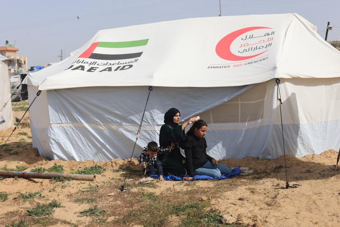 Rotana Al-Raqb avec deux de ses enfants, devant sa tente dans le camp de réfugiés d’Al-Mawassi (Gaza), le 13&nbsp;février&nbsp;2026.