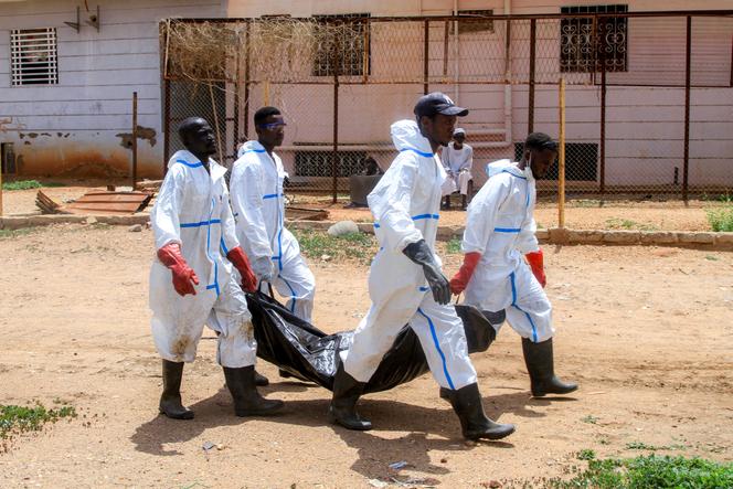 Membros do Crescente Vermelho Sudanês carregam os restos mortais exumados de uma pessoa de uma sepultura improvisada para novo enterro no cemitério local em Al-Azhari, um subúrbio ao sul de Cartum, em 2 de agosto de 2025, depois que os mortos foram enterrados às pressas quando a área estava sob o controle dos paramilitares das Forças de Apoio Rápido. 
