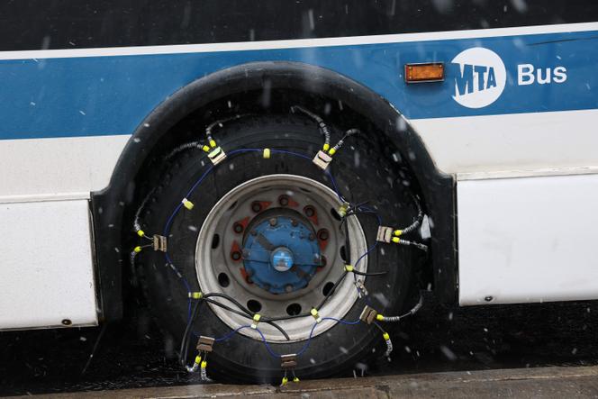 Um pneu de ônibus MTA fica coberto de correntes durante uma nevasca, no centro do Brooklyn, Nova York, em 22 de fevereiro de 2026.