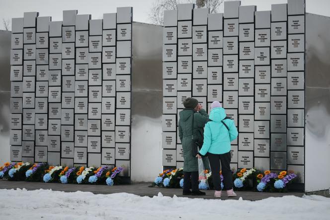Relatives of victims of the Russian occupation stand before the Wall of Remembrance during a ceremony marking four years since the Russian invasion of Ukraine, in Bucha, on February 24, 2026.