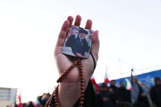 Un manifestant brandit une photo du Guide suprême iranien, l’ayatollah Ali Khamenei, tandis que des personnes en deuil se recueillent sur une place de Téhéran, le 1ᵉʳ mars 2026. 