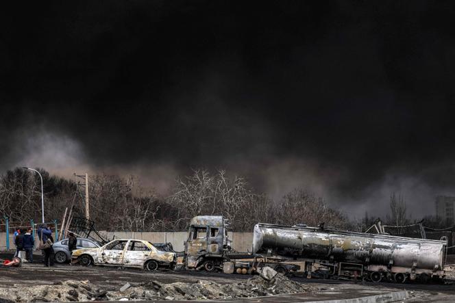 A dark smoke cloud engulfs destroyed vehicles near an ongoing fire following an overnight airstrike on the Shahran oil refinery in northwestern Tehran on March 8, 2026.