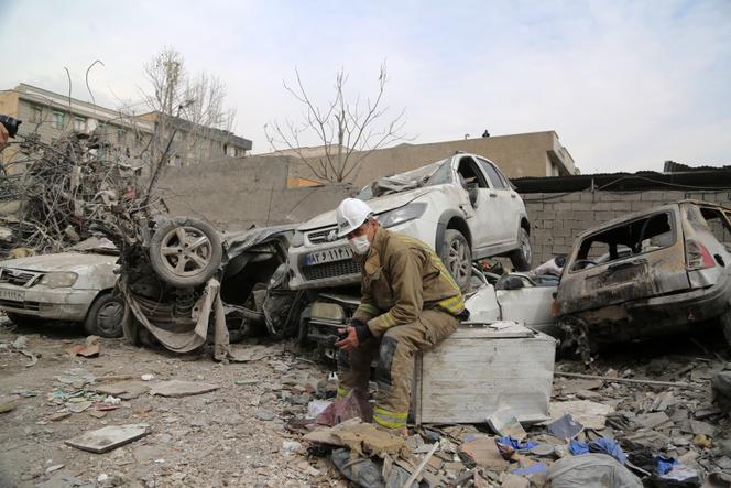 Un membre des équipes de recherche et de sauvetage est assis sur les décombres d’un bâtiment endommagé près de la place Risalat, à la suite des frappes israéliennes et américaines à Téhéran, le 12 mars 2026. 