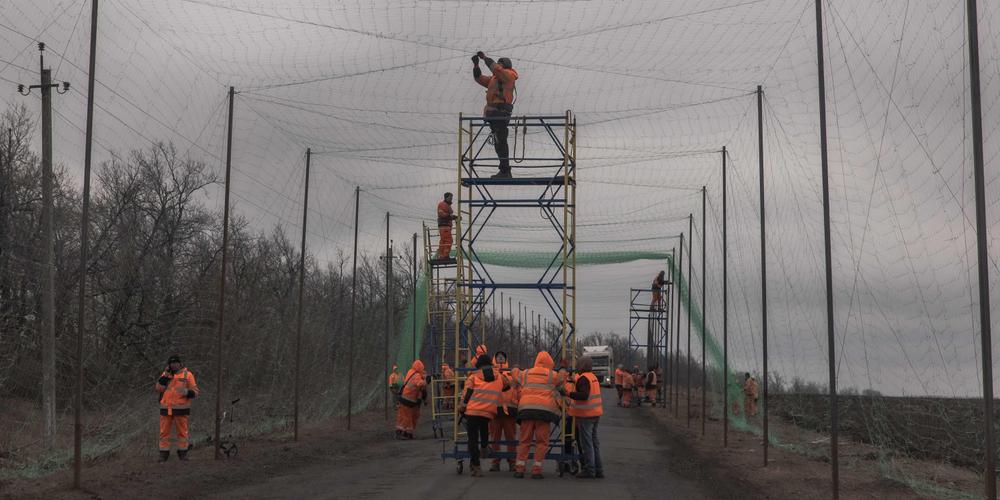 Des ouvriers ukrainiens installent des filets antidrones pour se protéger des attaques, dans la région de Kharkiv, le 17 mars 2026. - ROMAN PILIPEY / AFP