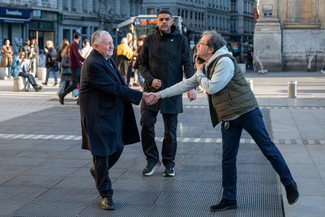 Jean-Michel Aulas, candidat de la droite et du centre à Lyon, salue un passant place des Terreaux avant d’aller regarder le match entre l’OL et le Celta Vigo dans une brasserie voisine, le 19 mars 2026.