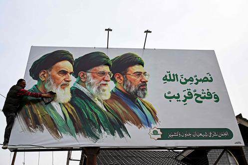 Panneau d’affichage représentant les anciens guides suprêmes iraniens, l’ayatollah Rouhollah Khomeiny (à gauche) et l’ayatollah Ali Khamenei (au centre), à ​​côté du nouveau guide suprême élu, l’ayatollah Mojtaba Khamenei, en périphérie de Srinagar (Inde), le 23 mars 2026.