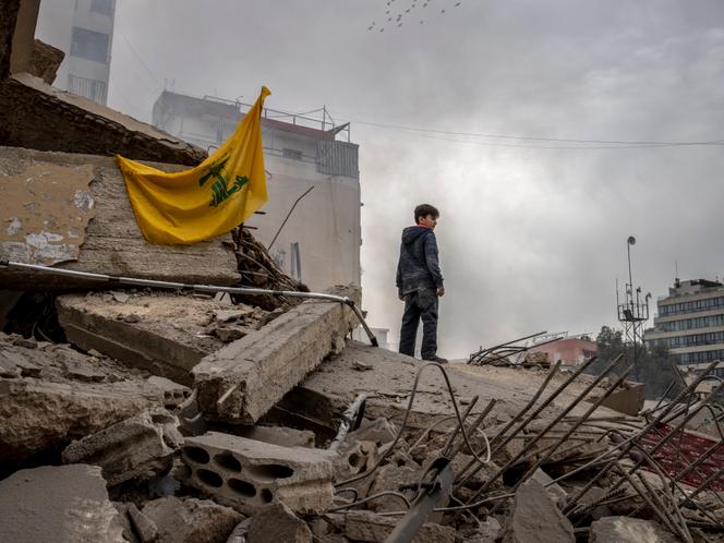 Un drapeau du Hezbollah est accroché sur les ruines d’un immeuble détruit par une frappe israélienne, à Beyrouth, le 18 mars 2026.