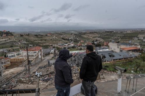 Deux habitants observent des bâtiments détruits par des frappes israéliennes à Nabi Chit (Liban), le 26 mars 2026.