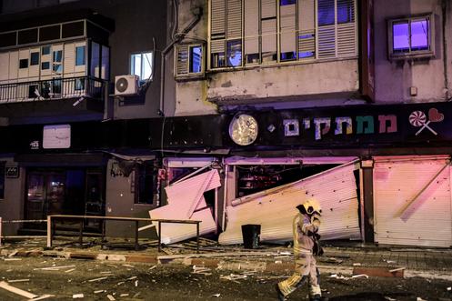 Devant des commerces endommagés par une frappe de missile iranien, dans le centre d’Israël, le 28 mars 2026.