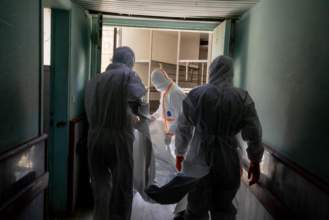 Membros do Crescente Vermelho Sírio carregam um cadáver em um saco para cadáveres até seu caminhão no hospital Souweida, Síria, em 23 de julho de 2025.