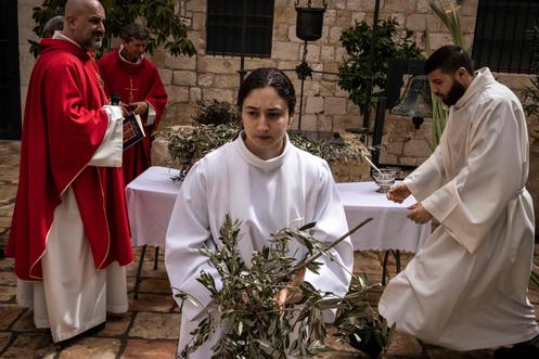 Os coroinhas distribuem ramos de oliveira, antes da procissão da missa do Domingo de Ramos, no mosteiro franciscano católico de Saint-Sauveur, em Jerusalém, em 29 de março de 2026.