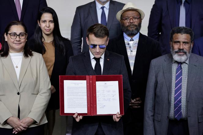 Emmanuel Macron apresenta o acordo Elysée-Oudinot, ao lado de Naïma Moutchou (à esquerda ao fundo), do ministro francês dos Negócios Estrangeiros, Victor Tutugoro (ao fundo à direita), presidente da União Progressista na Melanésia, e Adolphe Digoué (à direita), membro do Partido de Libertação Kanak (Palika), no Palácio do Eliseu, em Paris, 19 de janeiro de 2026.