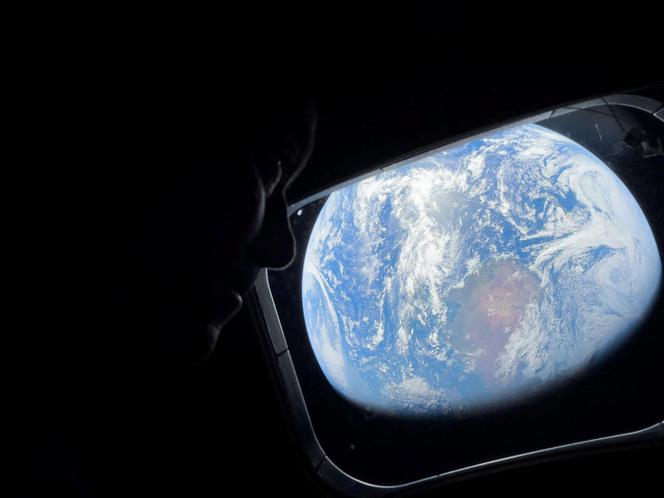 NASA astronaut and Artemis II Commander Reid Wiseman peers out of one of the Orion spacecraft's main cabin windows, looking back at Earth, as the crew travels towards the Moon, April 2, 2024. 