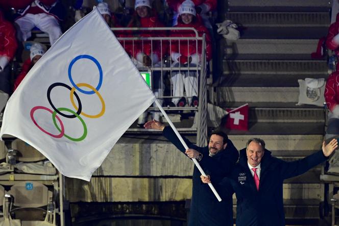 Fabrice Pannekoucke (à esquerda), presidente da região de Auvergne-Rhône-Alpes, e Renaud Muselier, presidente da região de Provence-Alpes-Côte d'Azur, agitam a bandeira olímpica durante a cerimônia de entrega da bandeira ao próximo anfitrião dos Jogos Olímpicos de Inverno de 2030, os Alpes Franceses, durante a cerimônia de encerramento dos Jogos Olímpicos de Inverno de Milão-Cortina de 2026, em 22 de fevereiro de 2026. 