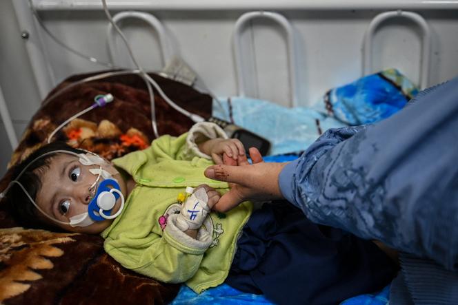Uma criança desnutrida segura a mão da mãe no centro de nutrição terapêutica dos Médicos Sem Fronteiras, localizado em um hospital em Herat, Afeganistão, em 8 de janeiro de 2026.