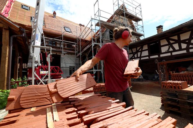 Trabalhadores trabalhando no telhado de uma casa tradicional da Alsácia, em Uttwiller (Baixo Reno), 22 de maio de 2024.