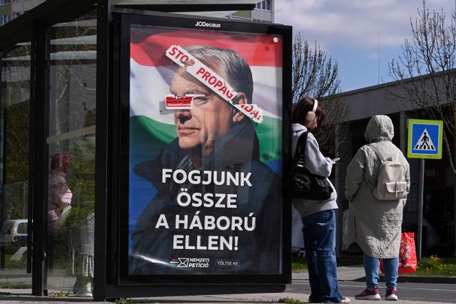 Um cartaz eleitoral do primeiro-ministro húngaro, Viktor Orban, com o slogan “Vamos nos unir contra a guerra” (em baixo), no qual foi colada a inscrição “Parem a propaganda” (em cima), em Budapeste, 9 de abril de 2026. 