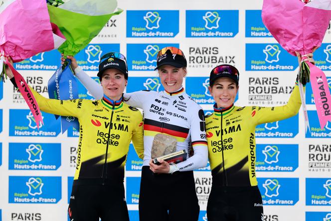 Franziska Koch comemora sua vitória durante a 6ª edição feminina do Paris-Roubaix, no dia 12 de abril de 2026, ao lado de Marianne Vos (esquerda) e Pauline Ferrand-Prévot (direita).
